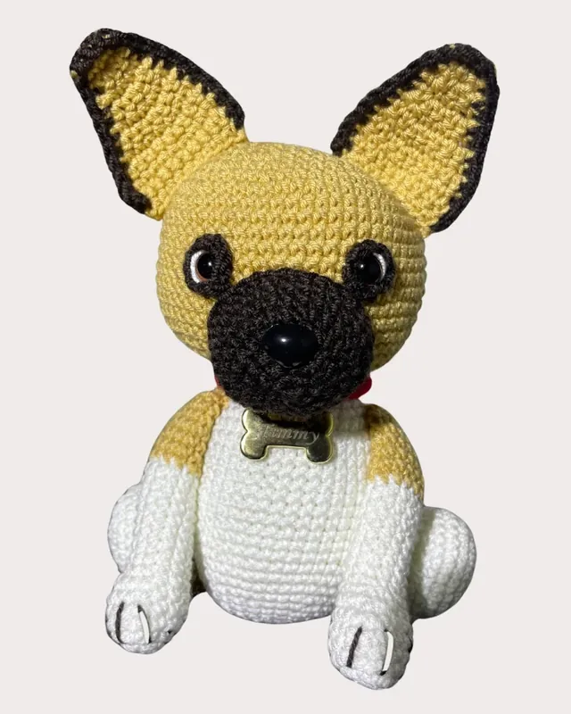 Amigurumi de un bulldog francés con su placa de nombre, tejido a mano