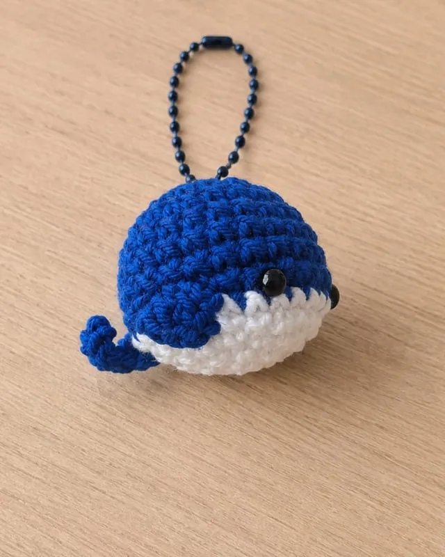 Llavero de ballena azul tejido a mano en crochet sobre una mesa de madera