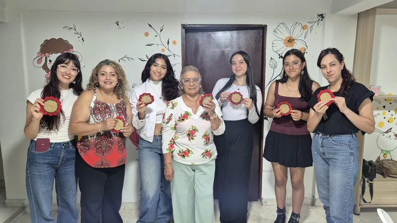 Grupo de participantes mostrando sus posavasos tejidos a mano en el taller