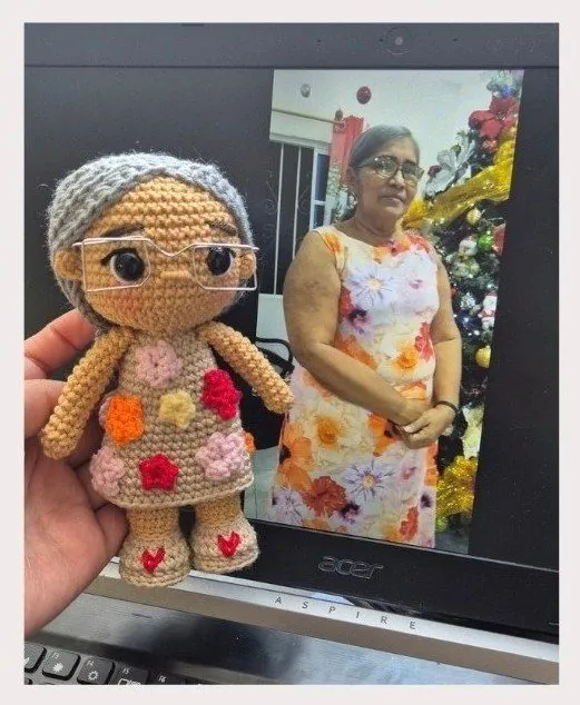 Abuela con vestido de flores y gafas, junto a su amigurumi personalizado con los mismos detalles