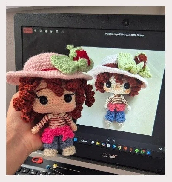 Muñeca con sombrero de fresa usada como referencia, junto al amigurumi tejido a partir de ella